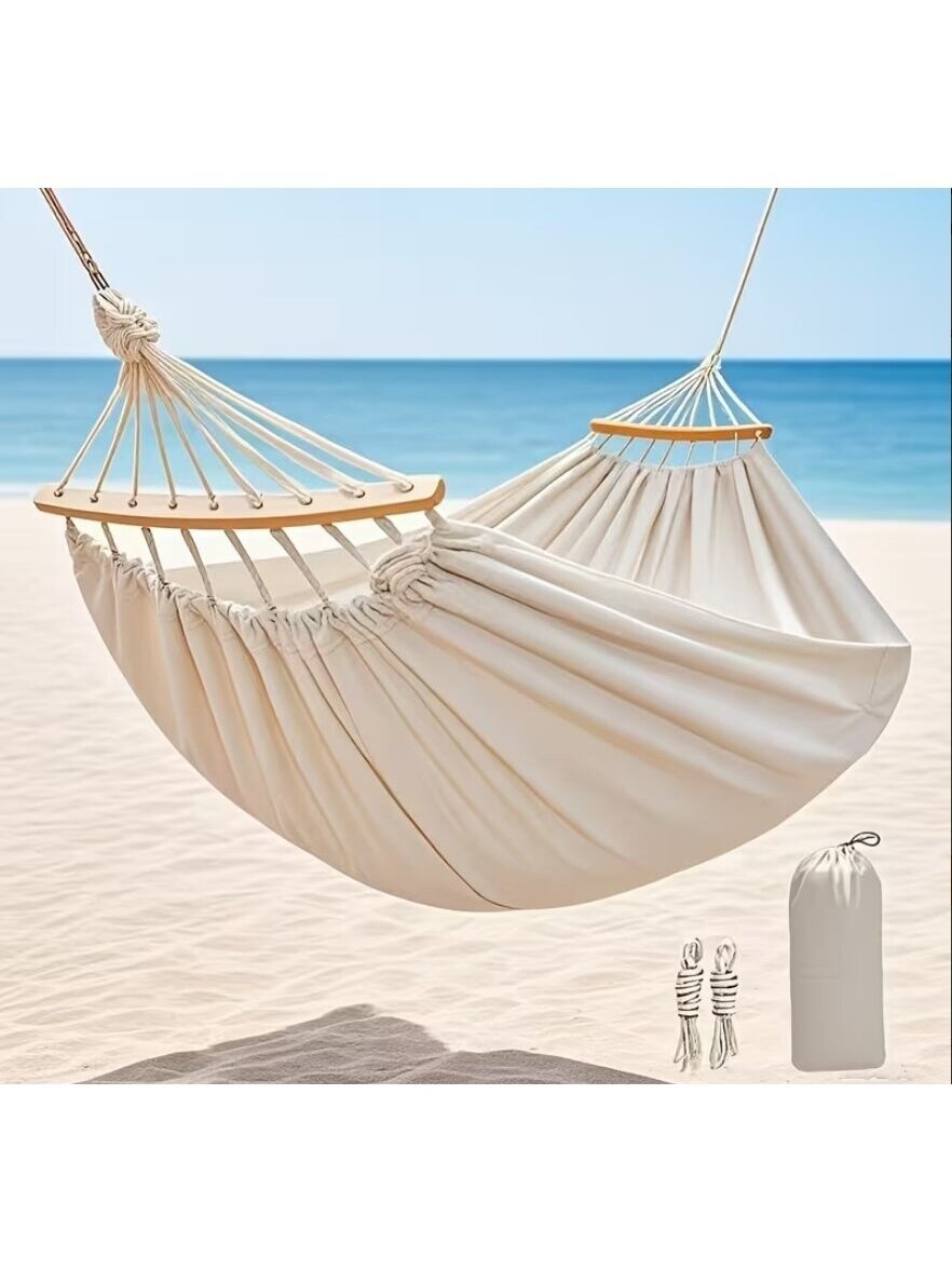 Outdoor canvas hammock with curved stabilization bars.